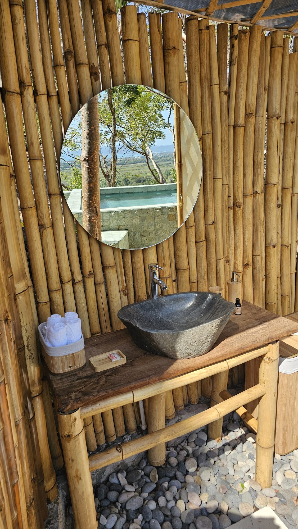 Lavabo de piedra de río y espejo que refleja la alberca y el valle