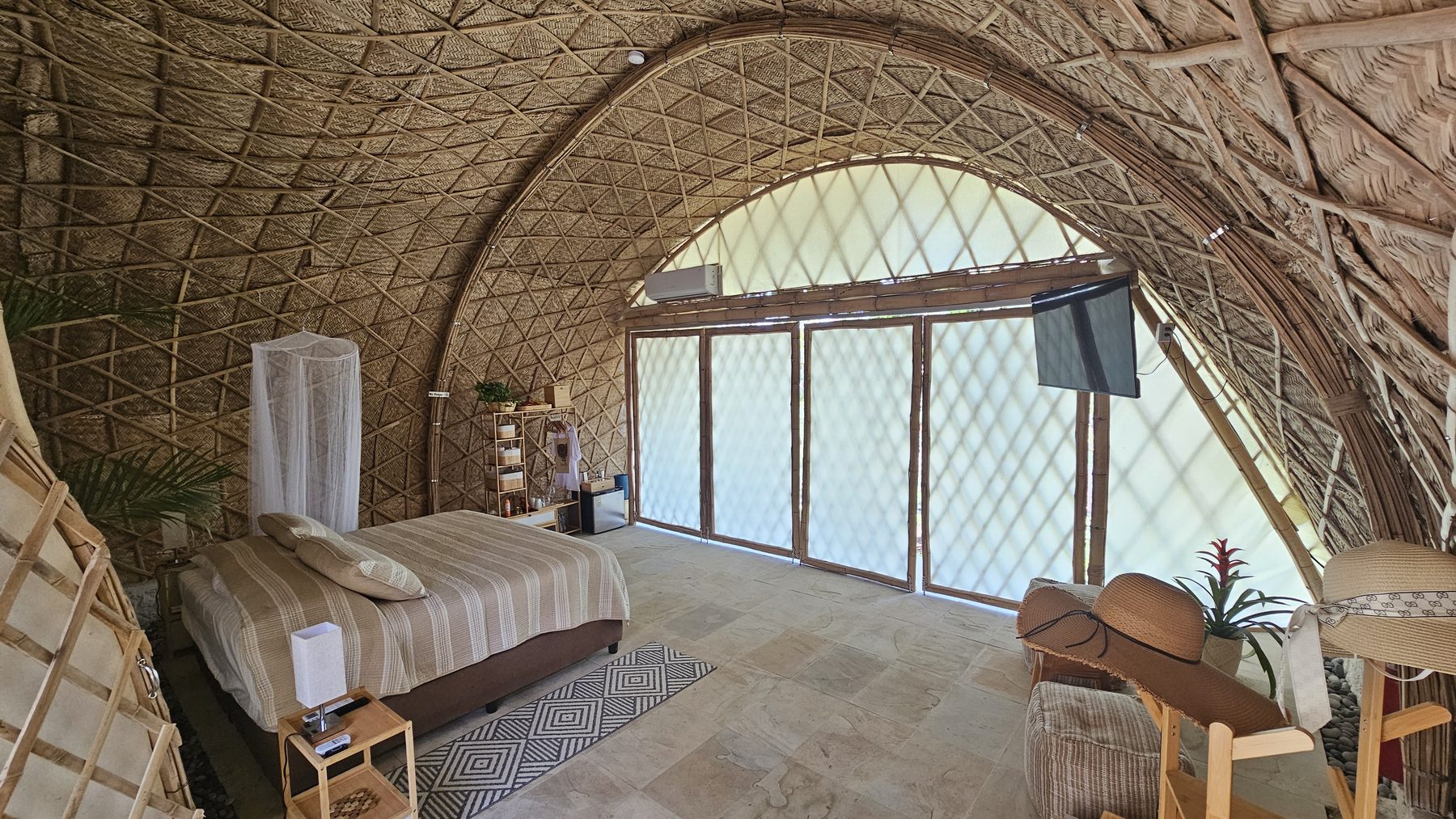 Interior del domo de bambú con la cama y las puertas abiertas