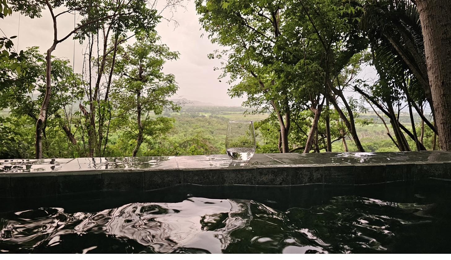 Vaso al borde del jacuzzi con el valle bajo la lluvia